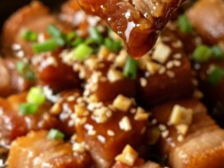 Sticky honey soy garlic pork belly bites with sesame and scallions in a skillet