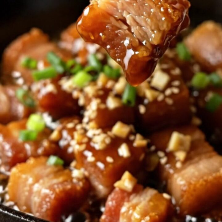 Sticky honey soy garlic pork belly bites with sesame and scallions in a skillet