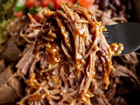 Overhead view of a burrito bowl with shredded barbacoa beef, cilantro lime rice, black beans, corn, avocado