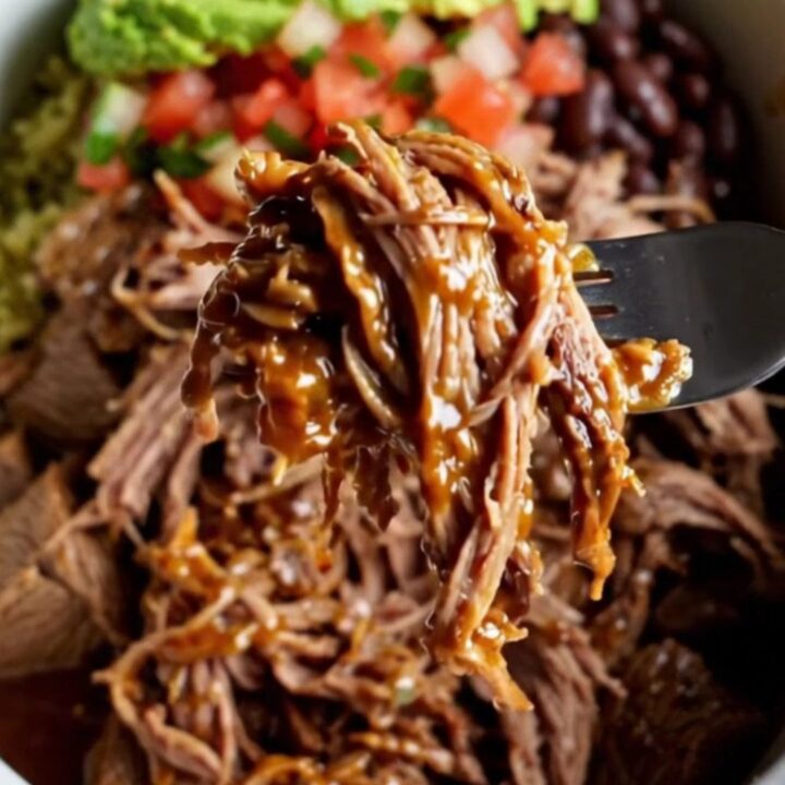 Overhead view of a burrito bowl with shredded barbacoa beef, cilantro lime rice, black beans, corn, avocado