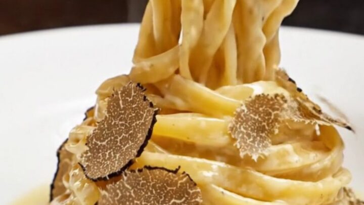 Twirl of fresh fettuccine in a hollowed Grana Padano wheel with melted cheese and truffle shavings