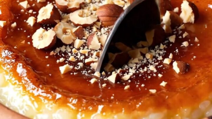 Caramelized Turkish baked rice pudding in a clay bowl with a blistered brown top and crushed hazelnuts