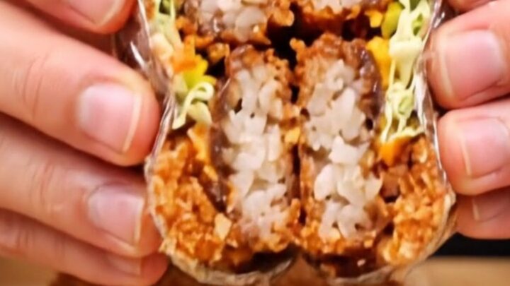 Cross-section of a crispy tonkatsu onigirazu showing layers of rice, cabbage, katsu, and sauce.