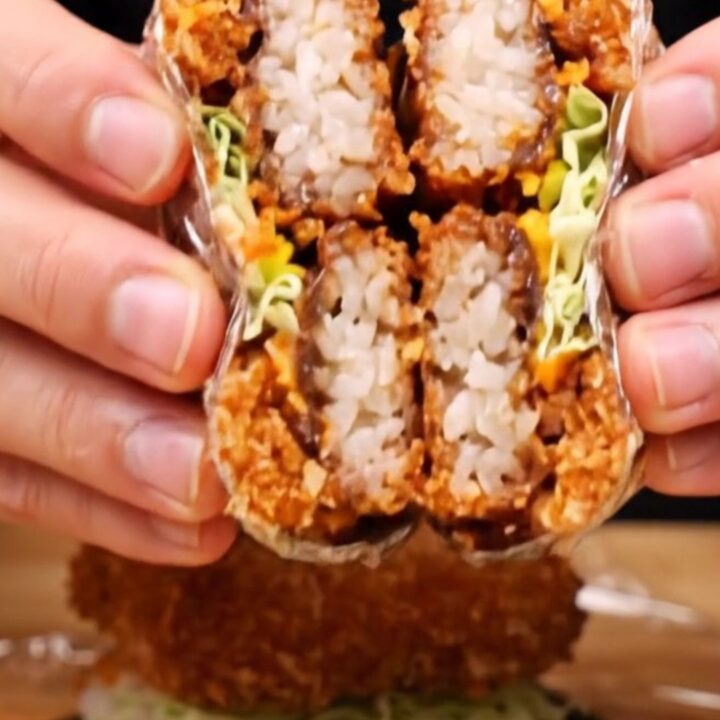 Cross-section of a crispy tonkatsu onigirazu showing layers of rice, cabbage, katsu, and sauce.