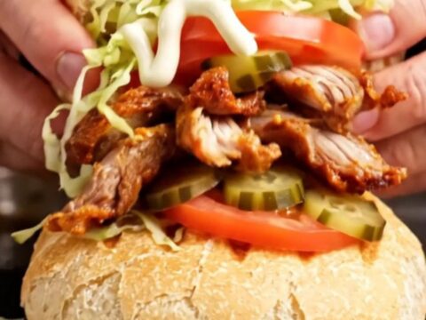 A Turkish chicken döner wrap with crispy chicken slices, lettuce, tomatoes, and pickles in toasted tombik bread