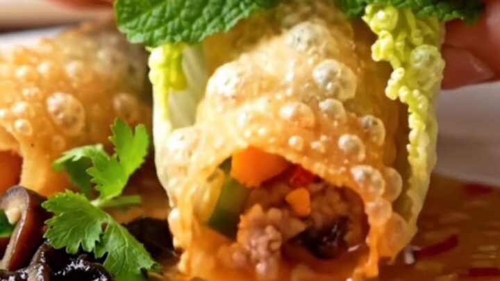Crispy golden rice paper spring rolls arranged on a plate with a bowl of Nuoc Cham dipping sauce.