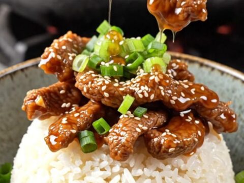 Crispy sesame beef rice bowl with sticky ginger soy glaze, topped with scallions and sesame seeds