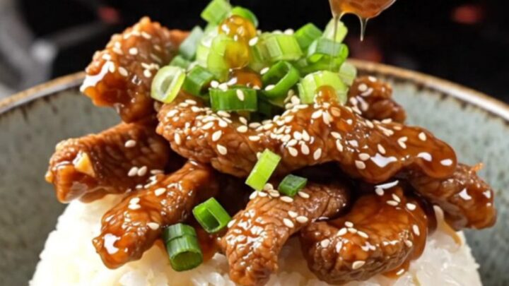 Crispy sesame beef rice bowl with sticky ginger soy glaze, topped with scallions and sesame seeds