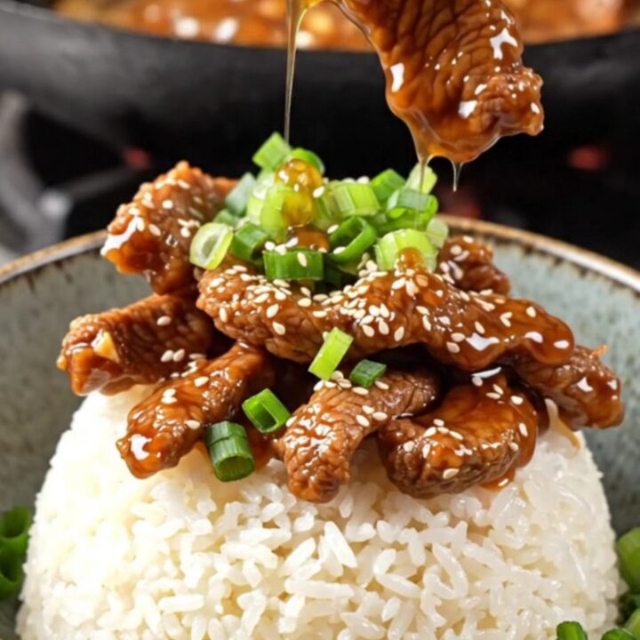 Crispy sesame beef rice bowl with sticky ginger soy glaze, topped with scallions and sesame seeds