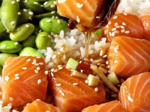 Glazed teriyaki salmon bites over jasmine rice with edamame, topped with sesame seeds.