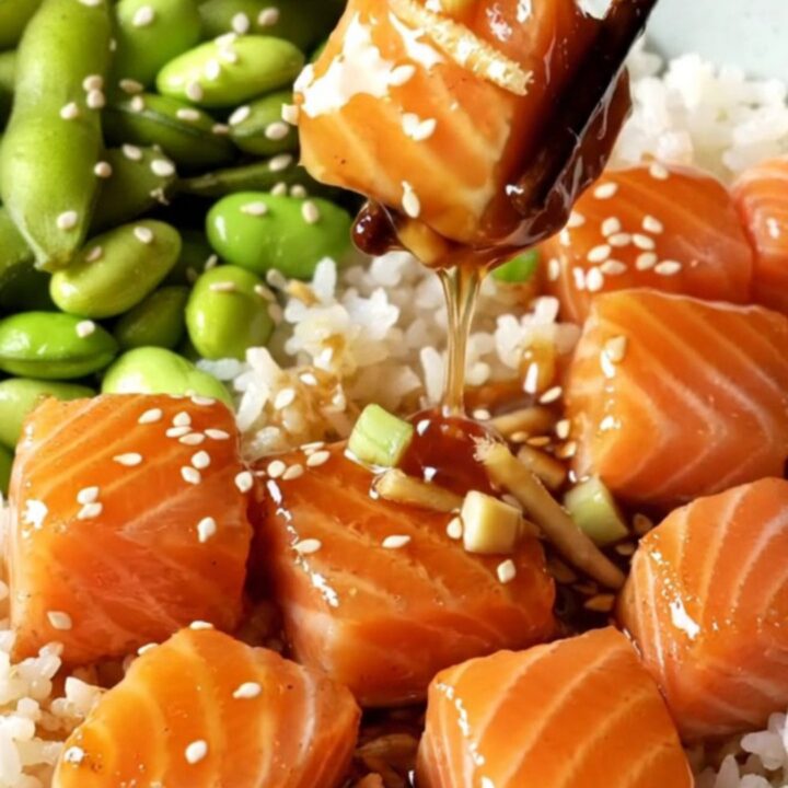 Glazed teriyaki salmon bites over jasmine rice with edamame, topped with sesame seeds.
