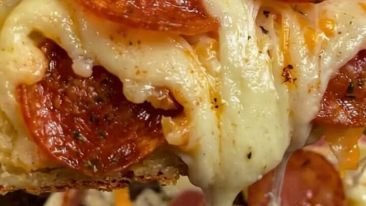 A golden brown, freshly baked cheesy potato roll stromboli on a rustic wooden board with visible melted mozzarella.