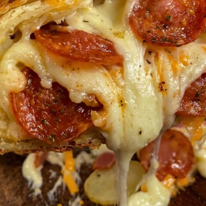 A golden brown, freshly baked cheesy potato roll stromboli on a rustic wooden board with visible melted mozzarella.