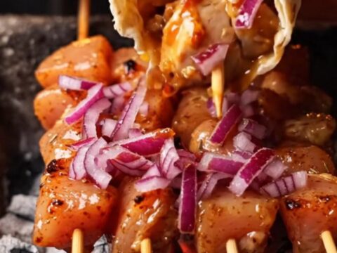 Grilled chicken skewers on a plate with lavash and sumac onions