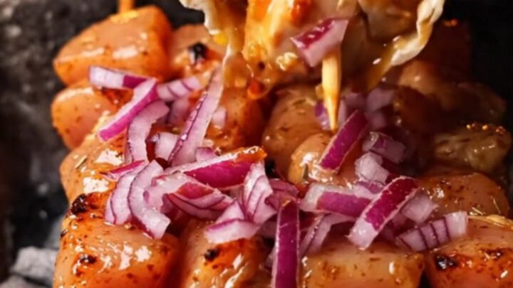 Grilled chicken skewers on a plate with lavash and sumac onions