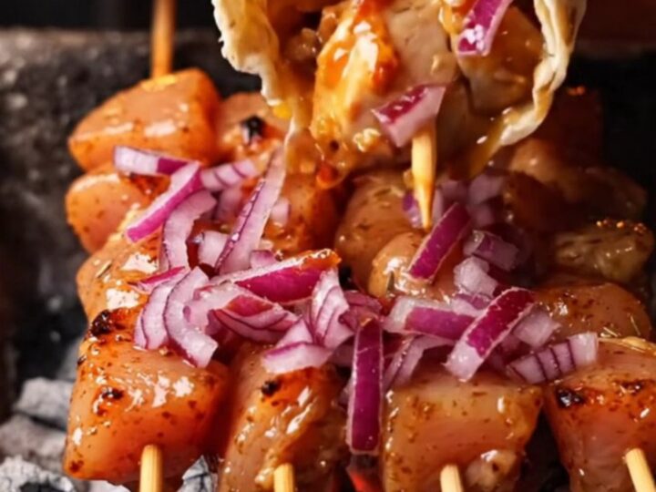Grilled chicken skewers on a plate with lavash and sumac onions