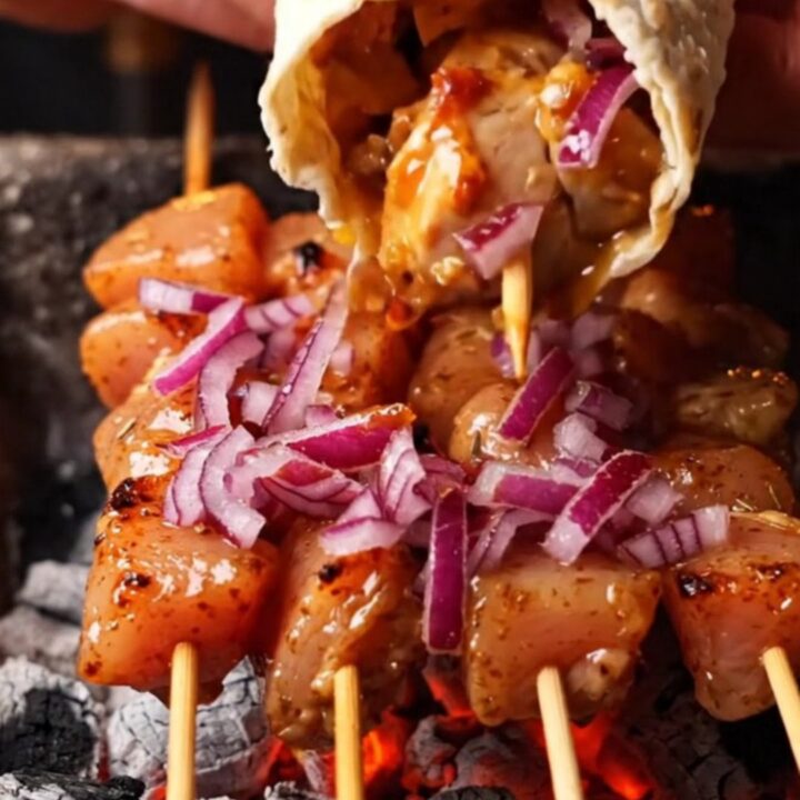 Grilled chicken skewers on a plate with lavash and sumac onions