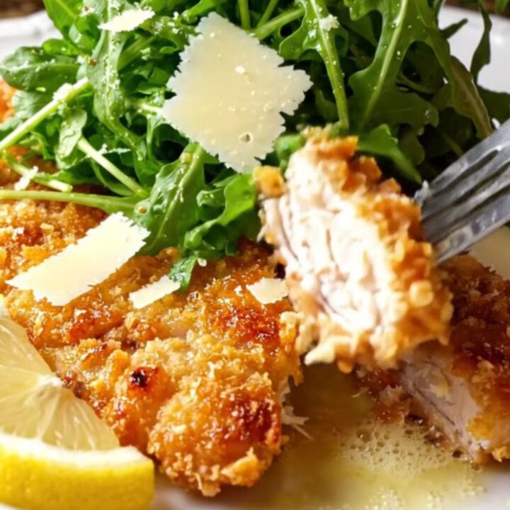 Golden crispy chicken cutlets topped with lemon arugula salad and shaved parmesan