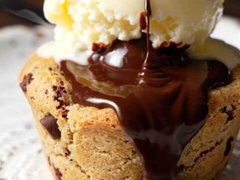 Warm chocolate chip cookie cup with molten chocolate lava flowing out, topped with a scoop of vanilla bean gelato