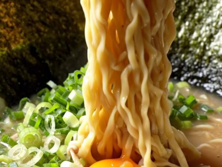 A bowl of tonkotsu ramen with chashu, jammy egg, nori, and scallions in creamy broth