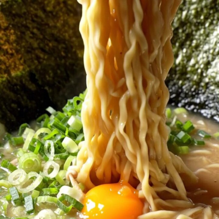 A bowl of tonkotsu ramen with chashu, jammy egg, nori, and scallions in creamy broth