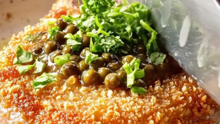 Crispy fried pork chop with creamy peppercorn sauce spooned over, garnished with parsley.