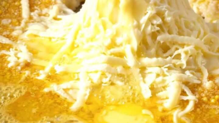 A copper pan of Karadeniz Mıhlama with melted cheese and butter, a piece of bread pulling a long cheese strand.