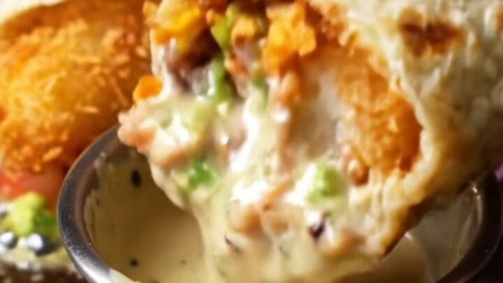 Crispy Baja fish burrito sliced in half showing golden cod, rice, beans, guacamole, and purple cabbage