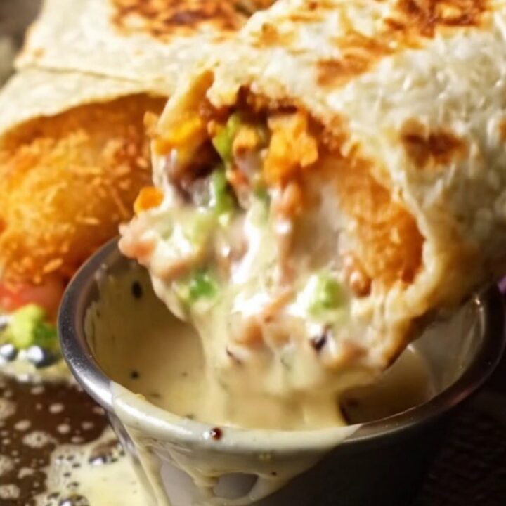 Crispy Baja fish burrito sliced in half showing golden cod, rice, beans, guacamole, and purple cabbage