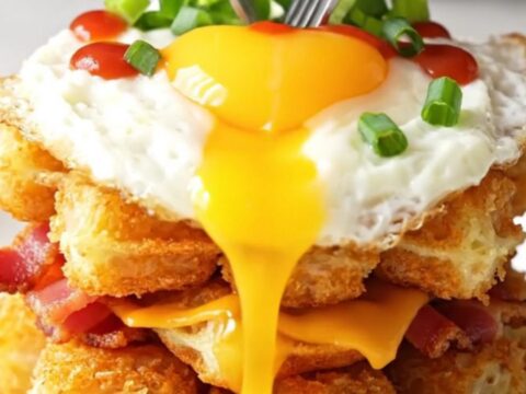 Crispy tater tot waffle topped with a fried egg, sriracha, and green onions