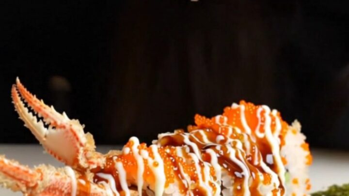 Crispy tempura soft-shell crab roll sliced into pieces, topped with tobiko and drizzled with sauces