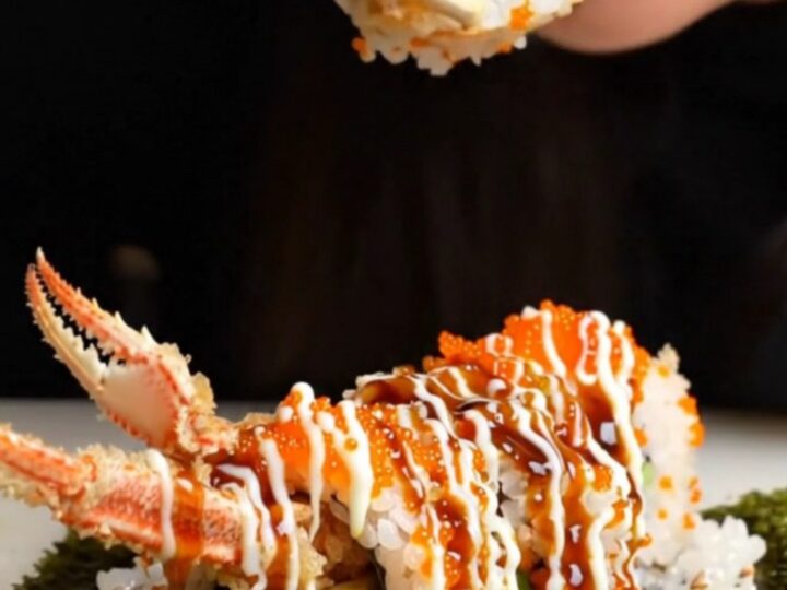 Crispy tempura soft-shell crab roll sliced into pieces, topped with tobiko and drizzled with sauces