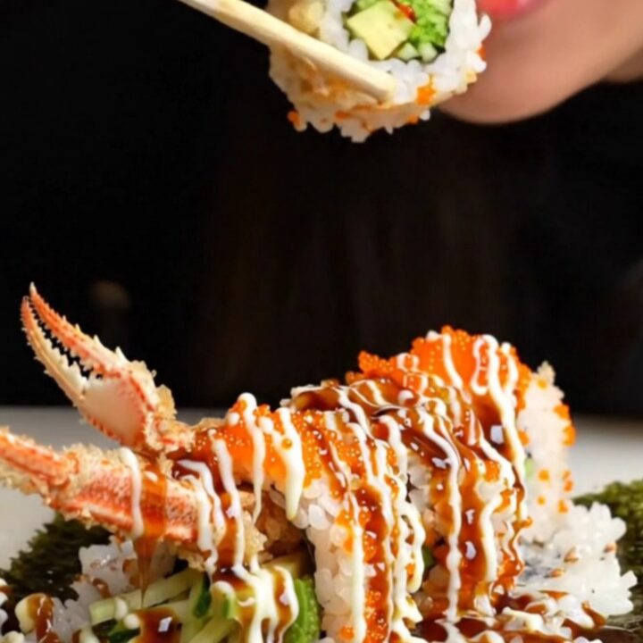 Crispy tempura soft-shell crab roll sliced into pieces, topped with tobiko and drizzled with sauces