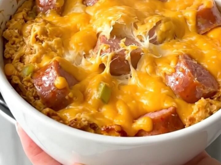 Crockpot cheesy bratwurst beer dip in a white bowl with a spoon