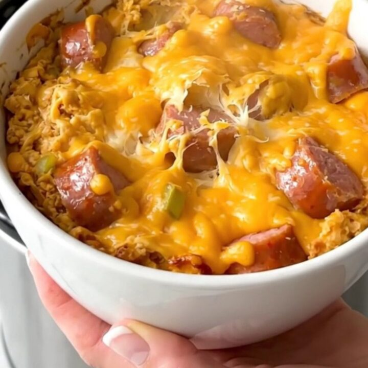 Crockpot cheesy bratwurst beer dip in a white bowl with a spoon