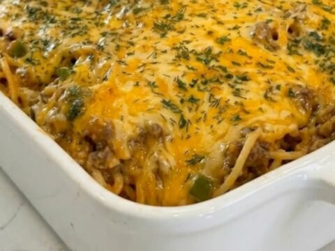 White ceramic dish of taco spaghetti casserole with melted golden cheddar and parsley