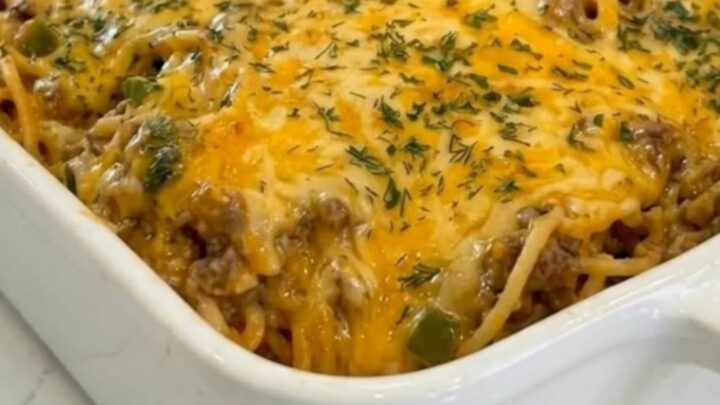 White ceramic dish of taco spaghetti casserole with melted golden cheddar and parsley