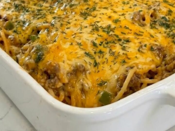 White ceramic dish of taco spaghetti casserole with melted golden cheddar and parsley