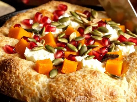 Golden focaccia topped with roasted butternut squash, crumbled goat cheese, sage leaves, pepitas, and pomegranate seeds.