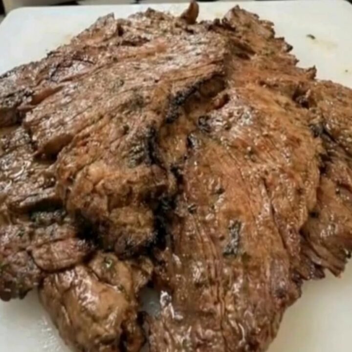 Juicy marinated flank steak sliced thin on a white plate