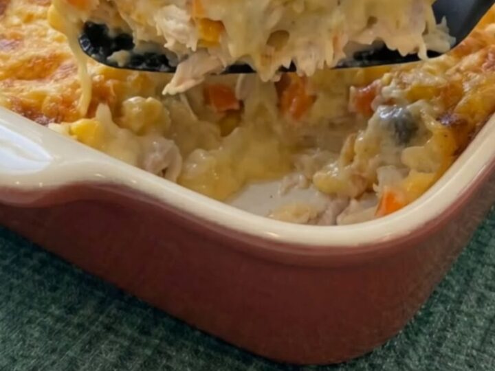 Cuillère soulevant une portion de chicken cobbler crémeux avec du fromage filant et une croûte dorée.