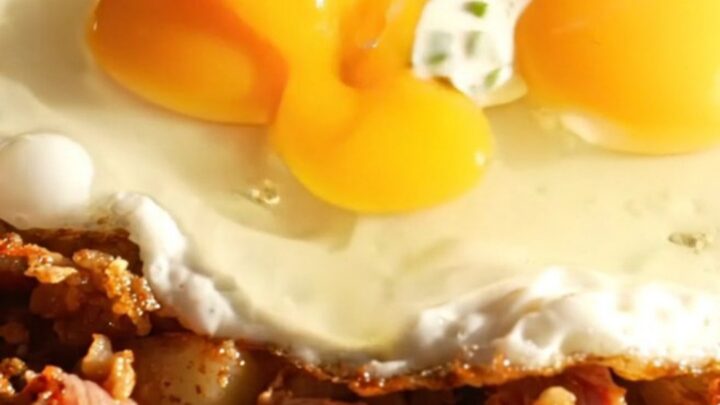Crispy corned beef hash with two fried eggs and horseradish chive crema in a cast-iron skillet