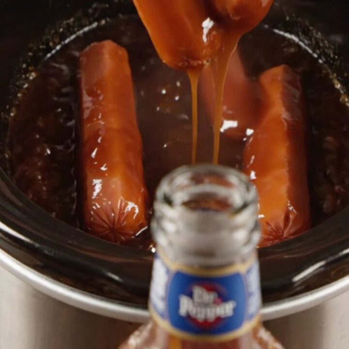 Glossy Dr Pepper BBQ Lil' Smokies in a slow cooker with a dark, syrupy sauce
