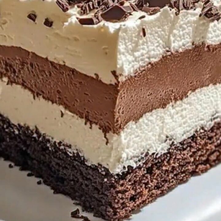 A slice of triple chocolate mousse cake with visible layers of sponge, chocolate mousse, and cream.