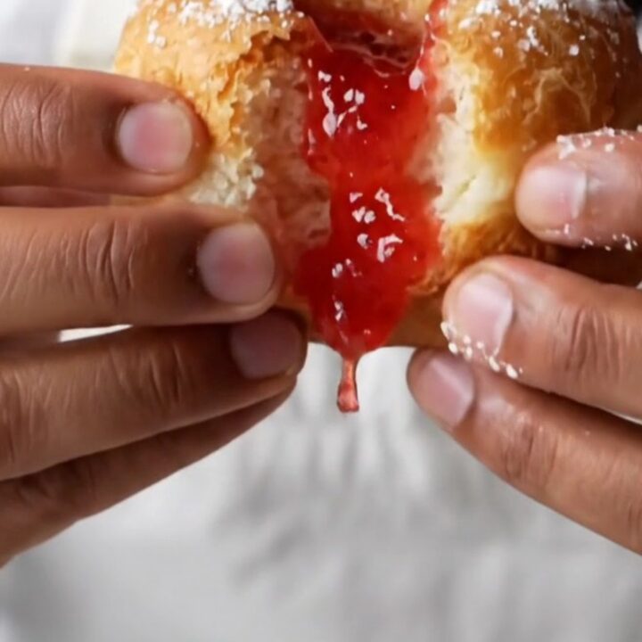 Golden sugar-dusted Berliner donuts with strawberry jam oozing from the center