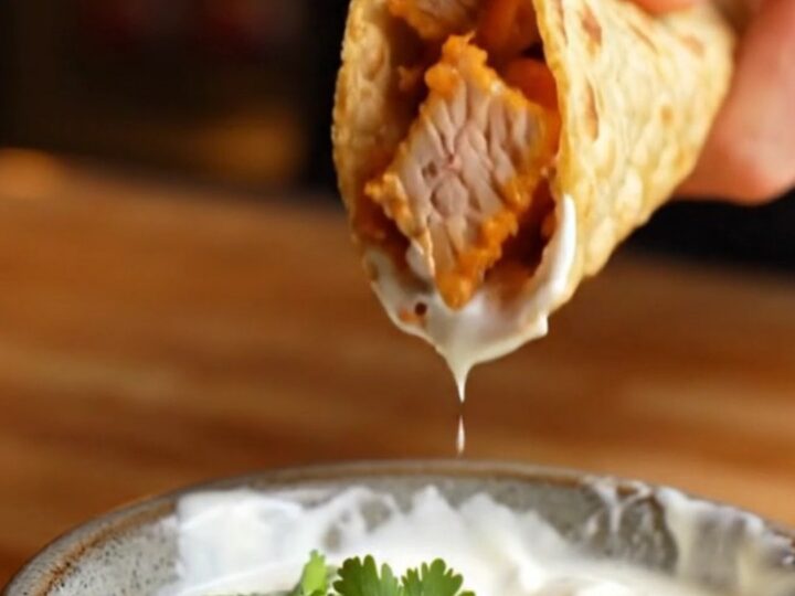 Crispy folded chipotle chicken taco lifted from a sheet pan, with melted cheese stretching