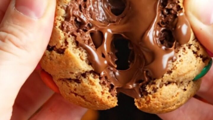 Thick bakery-style M&M cookies with golden edges and soft centers, studded with colorful candies and chocolate chunks.