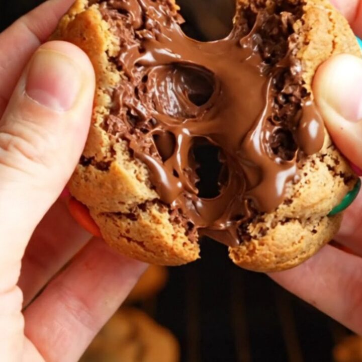 Thick bakery-style M&M cookies with golden edges and soft centers, studded with colorful candies and chocolate chunks.