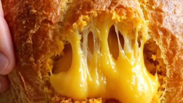 Golden-brown pumpkin-shaped brioche buns with feta cheese filling, one pulled apart showing melted cheese