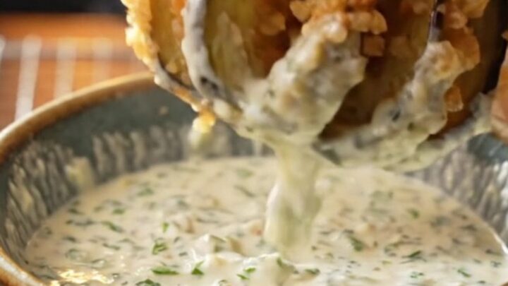 Golden accordion eggplant fries with garlic yogurt dip on a wooden board
